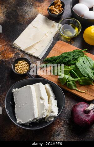 Traditionelle griechische spanakopita Zutaten Filo Spinat Eier Feta Seitenansicht auf dunklem Hintergrund Stockfoto