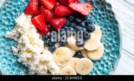 Morgenvergnügen. Gesundes Sommerfrühstück. Hüttenkäse mit Beeren Früchte und Honig. Gemütliches, einfaches Frühstück Stockfoto