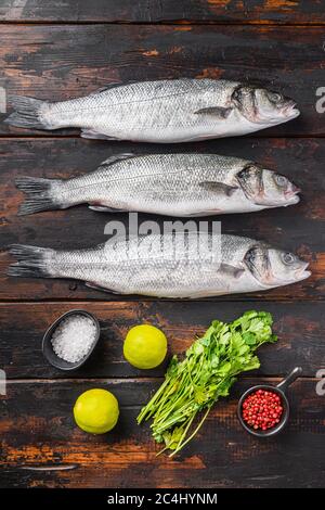 Frischer roher Seabass mit Gewürzen und Kräutern Zutaten auf altem Fischer dunklen Holztisch Draufsicht Stockfoto