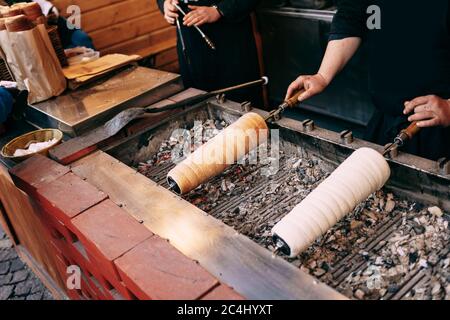 Street Food auf dem Weihnachtsmarkt in Budapest, Ungarn - Kurtoskalacs, die nationale klassische Gebäck, auch genannt - Baumkuchen, Trdelnik, Shakotis. Stockfoto