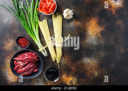 Rohzutaten für Rührei Nudeln mit Gemüse und Rindfleisch in schwarzer Schüssel braten. Auf alten rustikalen Tisch. Mit Platz für Text Stockfoto