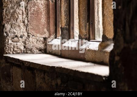 Von unten aus hat man einen Blick auf ein Fenster in einem alten Gebäude. Steinarbeiten Konstruktion ist im Vordergrund und entfernten Bäumen vor dem Fenster zu sehen. Stockfoto