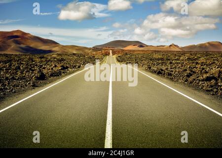 Keine Menschen, keine Tiere, keine Vegetation. Nur ich, die Straße und der blaue Himmel in der Mitte eines vulkanischen Lavameeres Stockfoto