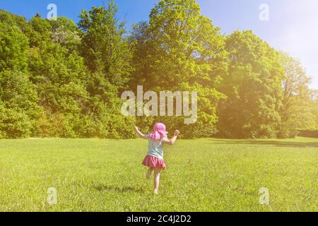 Junge glückliche Kind Spaß und Tanz auf einer grünen Wiese im Frühjahr an einem sonnigen Tag Stockfoto