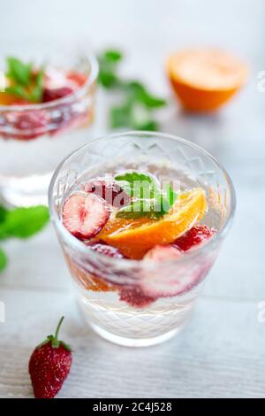 Sommercocktail mit Erdbeere, Orange und Minze im Glas auf weißem Tisch, hausgemachte erfrischende Limonade, Erdbeerpunsch, Kopierraum. Stockfoto