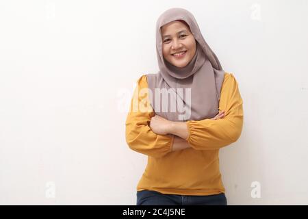 Portrait der asiatischen muslimischen Frau trägt Hijab freundlich lächelnd mit gekreuzten Armen, selbstbewusste Geste, erfolgreiche Geschäftsfrau, isoliert auf weiß Stockfoto