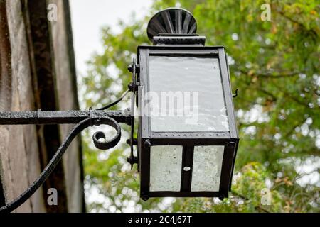 Nahaufnahme einer antiken, schmiedeeisernen Laterne mit elektrischen Wänden, die außerhalb eines alten, historischen Gebäudes gesehen wird. Stockfoto