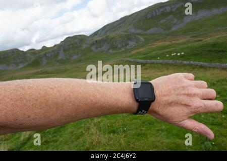 Erwachsener Mann, der einen beliebten Fitness-Tracker am linken Handgelenk trägt. Der Mann ist ein Trailrunner und schaut in angezeigte Statistiken. Stockfoto