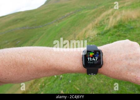 Erwachsener Mann, der einen beliebten Fitness-Tracker am linken Handgelenk trägt. Der Mann ist ein Trailrunner und schaut in angezeigte Statistiken. Stockfoto