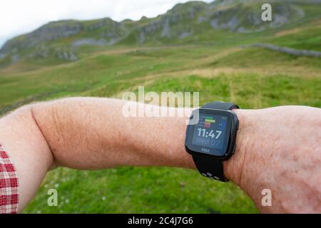 Erwachsener Mann, der einen beliebten Fitness-Tracker am linken Handgelenk trägt. Der Mann ist ein Trailrunner und schaut in angezeigte Statistiken. Stockfoto