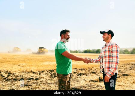 Bauer und Agronom schüttelt sich nach Absprache die Hände im Weizenfeld. Vertragskonzept für die Landwirtschaft. Firmenfarmer und Vermieter Rancher Stockfoto