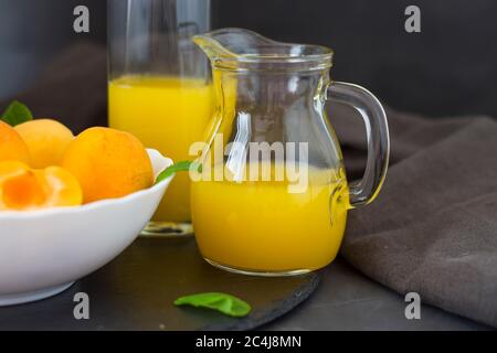 Sommer Aprikosensaft. Frischer Pfirsichsaft. Pfirsiche in einem weißen Teller. Daneben ist eine Karaffe Saft. Copyspace Stockfoto