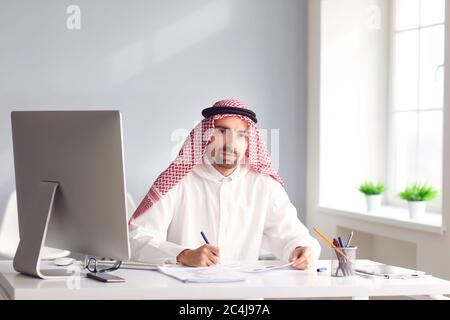 Ruhiger arabischer Mann sitzt an einem Tisch im Büro. A Stockfoto