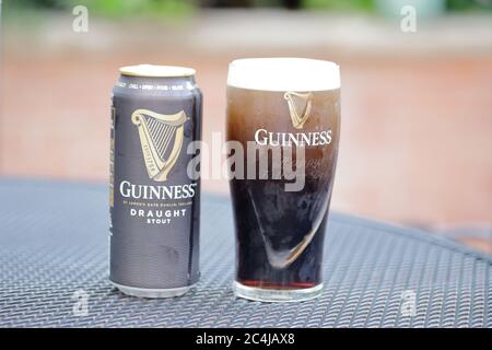 Ein gebrandmarkt Glas Guinness noch Settling und kann, draußen auf einem Terrassentisch Stockfoto