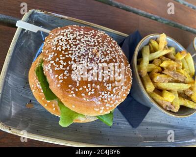 Nahaufnahme von isolierten Rindfleisch Burger mit Sesambrötchen und Schüssel mit pommes Frites auf dem Tisch Stockfoto