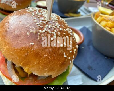 Nahaufnahme von isolierten Rindfleisch Burger mit Sesambrötchen und Schüssel mit pommes Frites auf dem Tisch Stockfoto