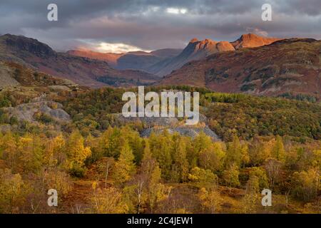 Die Langdale Pikes Mountain Range Bei Sonnenaufgang, Wenn Morgenlicht Aus Dunklen Moody Clouds Erleuchtet. Lake District, Großbritannien. Stockfoto