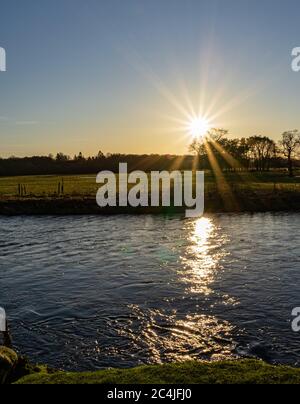 Die Sonne brach über dem Fluss Eamont mit der Sonne, die auf dem Fluss reflektiert Stockfoto