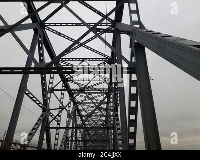 Metallkonstruktion der Eisenbahnbrücke mit dem aufsteigenden Mittelteil für die Durchfahrt von Schiffen. Blick von unten vom Fenster des Autos. Architektur, Designelemente Stockfoto