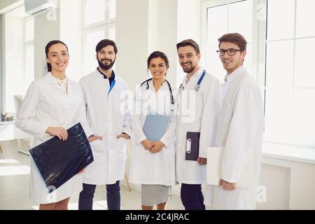 Gruppe junger Ärzte, die in der Krankenhaushalle zusammenstehen. Team von medizinischen Spezialisten lächeln an der Kamera in der Klinik Stockfoto