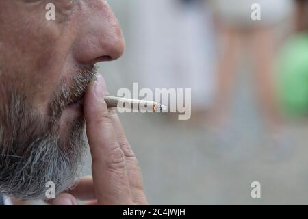 Bärtig ein Mann, der eine Zigarette rauchte. Nahaufnahme. Es gibt Outdoor-Profil Porträt mit selektivem Fokus. Stockfoto