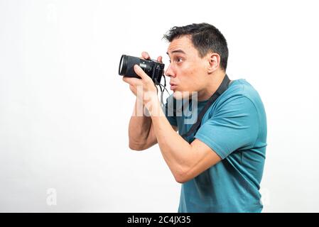 Mann mit Fotokamera, der etwas sehr konzentriertes fotografiert, Seitenansicht. Mittlerer Schuss. Weißer Hintergrund. Stockfoto