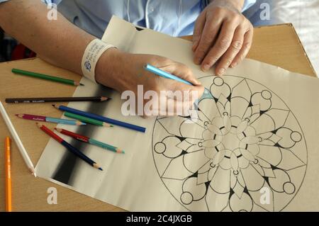 Im Krankenhaus eingewiesenen Frau verbringt sie ihre Freizeit Färbung Mandalas und andere Zeichnungen, hilft ihr zu entspannen und nicht zu denken. Stockfoto