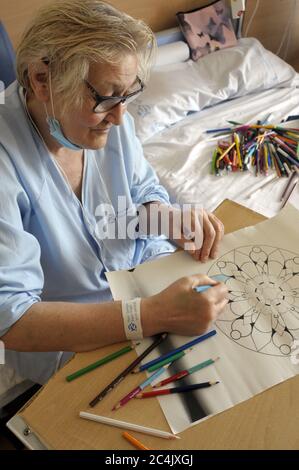 Im Krankenhaus eingewiesenen Frau verbringt sie ihre Freizeit Färbung Mandalas und andere Zeichnungen, hilft ihr zu entspannen und nicht zu denken. Stockfoto