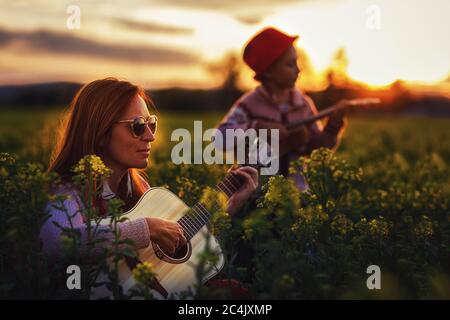 Mutter mit Töchtern, die mit Gitarre und Ukulele spielen. Stockfoto