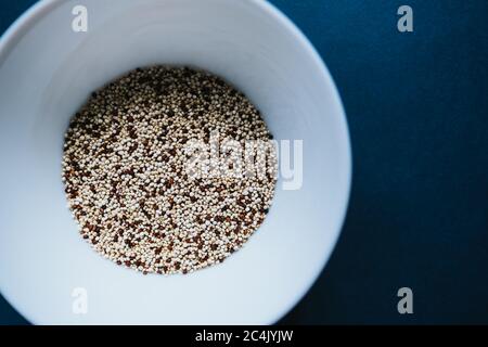 Quinoa-Haferbrei auf einem weißen Teller auf blauem Hintergrund. Stockfoto