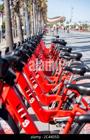 Barcelona, Spanien - 26. Juni 2020: Leuchtend rote Fahrräder zur Miete in einer Reihe in La Barceloneta geparkt. Konzept der ökologisch nachhaltigen tra Stockfoto