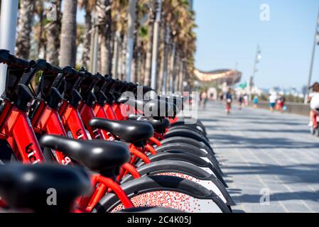 Barcelona, Spanien - 26. Juni 2020: Leuchtend rote Fahrräder zur Miete in einer Reihe in La Barceloneta geparkt. Konzept der ökologisch nachhaltigen tra Stockfoto