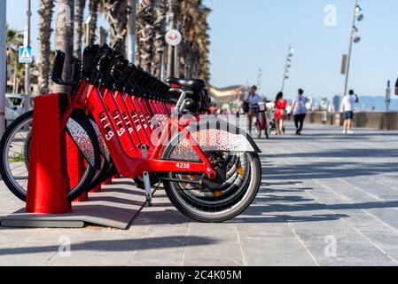 Barcelona, Spanien - 26. Juni 2020: Leuchtend rote Fahrräder zur Miete in einer Reihe in La Barceloneta geparkt. Konzept der ökologisch nachhaltigen tra Stockfoto