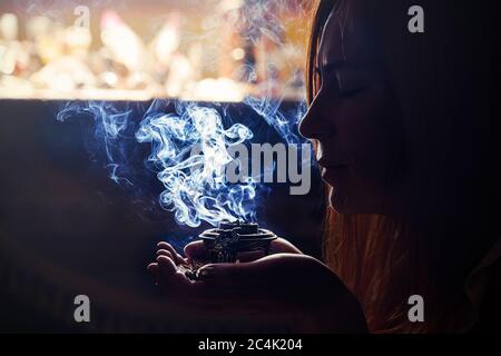 Weihrauch in der Hand einer Frau, Räucherstäbchen auf schwarzem Hintergrund. Stockfoto