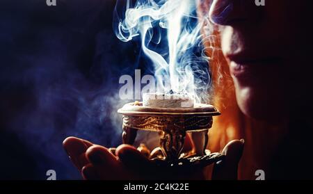 Weihrauch in der Hand einer Frau, Räucherstäbchen auf schwarzem Hintergrund. Stockfoto