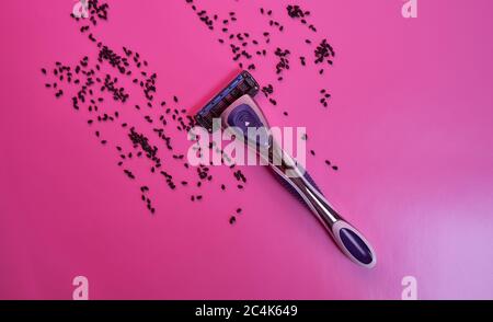 Rasiermaschine mit schwarzen Sesamsamen auf rosa Hintergrund. Mit Kopierbereich. Konzeptfoto. Stockfoto