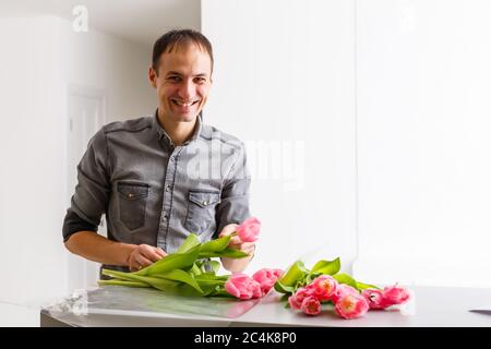 Blumen Lieferladen. Florist, der Ordnung schafft, Frühlingsstrauß macht. Männlich machen Bouquet mit Tulpen Stockfoto