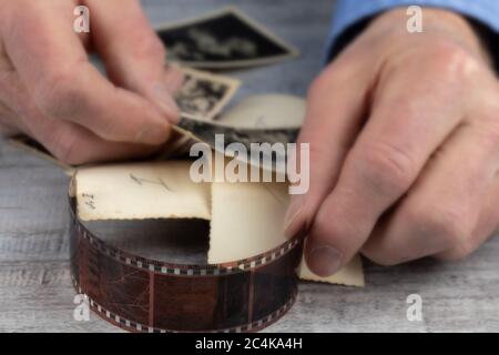 Ein älterer Mann, der alte Schwarzweißfotos in seinen rauen Händen hält Stockfoto