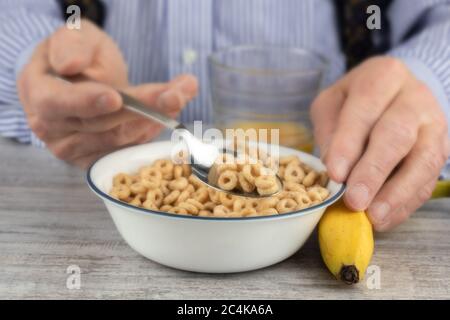 Nahaufnahme der Hände eines älteren Mannes, der einen Löffel voll Frühstückszerealien hält Stockfoto