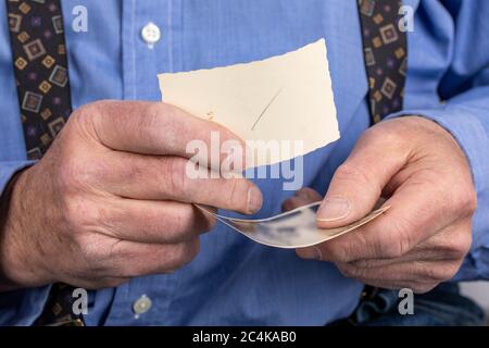 Ein älterer Mann, der alte Schwarzweißfotos in seinen rauen Händen hält Stockfoto