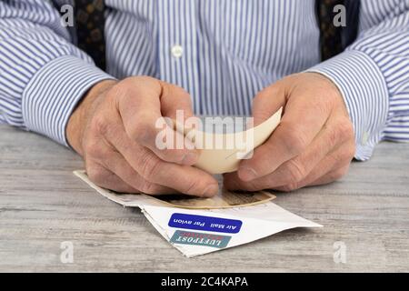 Nahaufnahme eines älteren Mannes, der Post von einem Verwandten aus Übersee liest, der per Luftpost geschickt wurde Stockfoto