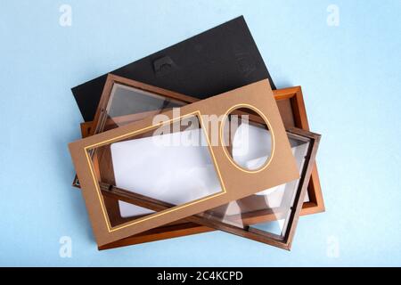 Draufsicht auf einen leeren Holzfotorahmen und Matte mit einem weiteren offenen Rahmen auf einem blauen Tisch Stockfoto