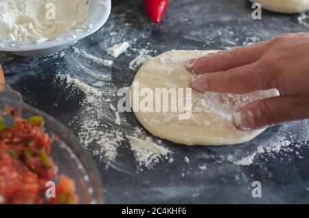 Hände, Mehl und Teig. Eine Frau bereitet einen Teig für das Backen zu Hause. Mehl den Teig und Tisch. Konzept der Hausmannskost, Backen zu Hause. Stockfoto
