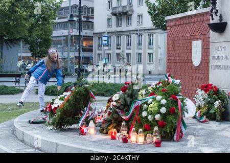 Győr, Ungarn - 04. Juni 2020: 100. Jahrestag des Vertrags von Trianon, ein kleines Mädchen legt Blumen an das Denkmal Stockfoto