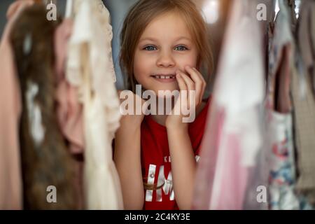 Soft Focus eines 5-6 Jahre alten Kindes Wahl ihrer eigenen Kleider aus Kinder Tuch Rack in Bekleidungsgeschäft Stockfoto