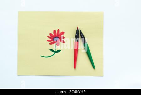Kinderzeichnung einer roten Blume auf gelbem Papier mit zwei Tintenmarkern, isoliert auf Weiß Stockfoto