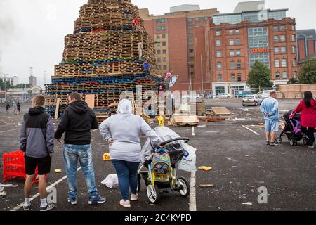 Anwohner beobachten, wie ein Lagerfeuer in Sandy Row, Belfast, Nordirland, gebaut wird. Stockfoto