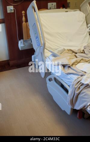 Leeres, nicht gemachtes Krankenhausbett rechts, mit Kopierplatz links, in einem örtlichen Krankenhaus Stockfoto