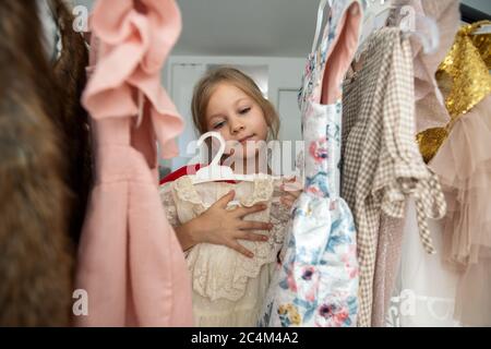 Nettes kleines Mädchen Auswahl Kleidung in Ankleidezimmer Stockfoto