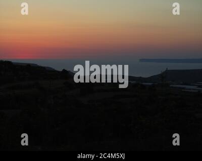 MGARR, MALTA - Jul 19, 2014: Maltese Valley und Meer in der Dämmerung, mit einem roten Himmel und Wolken am Horizont, Foto über terrassenförmig angelegten Feldern mit Klippen in der b Stockfoto